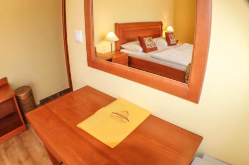 a room with a table with a mirror and a bed at Hotel Járja in Hajdúszoboszló