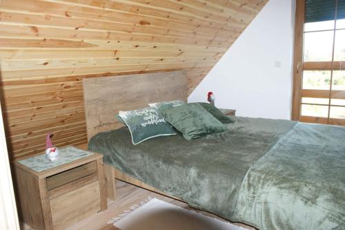 a bedroom with a bed and a wooden wall at Lavender Cottage in Charzykowy