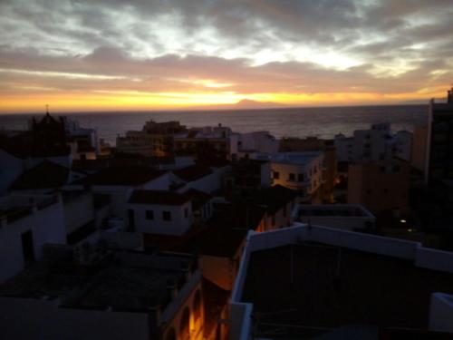una puesta de sol sobre una ciudad con edificios y el océano en Apartamento Playa Nueva, en Santa Cruz de la Palma
