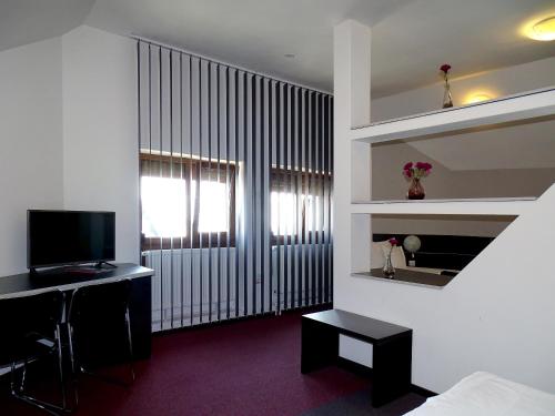 um quarto com uma cama, uma secretária e uma televisão em Prince Hotel em Miercurea-Ciuc