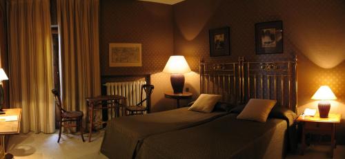a bedroom with a bed and two lamps and chairs at La Posada de Don Mariano in Pedraza-Segovia