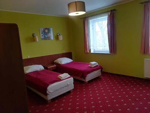 two beds in a room with green walls and a window at Hotel E-lektor in Morąg