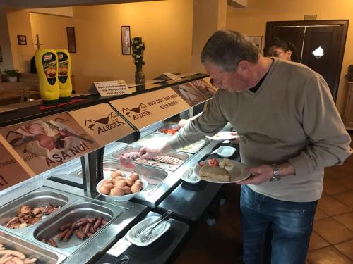 a man holding a plate of food in a buffet at Complex Pastravaria Albota in Arpaşu de Sus