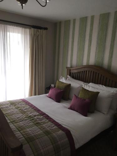 a bedroom with a large bed with purple and green pillows at The Judds Folly Hotel, Sure Hotel Collection by Best Western in Faversham