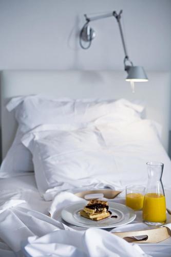a plate of food on a bed with two glasses of orange juice at The Majestic Hotel in Fira