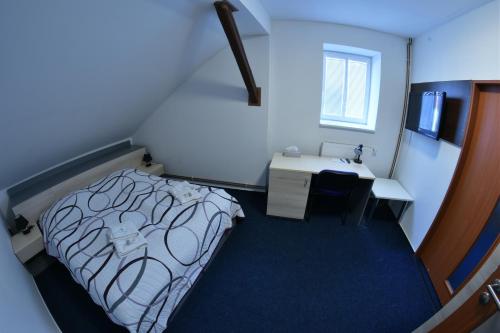 a small room with a bed and a desk at Penzion Grasel in Nové Syrovice