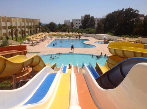 a large swimming pool with people in a water park at Dar Khayam in Hammamet