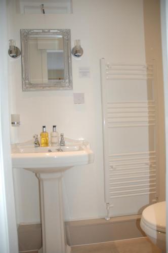 a white bathroom with a sink and a mirror at Lubnaig Guest House in Callander