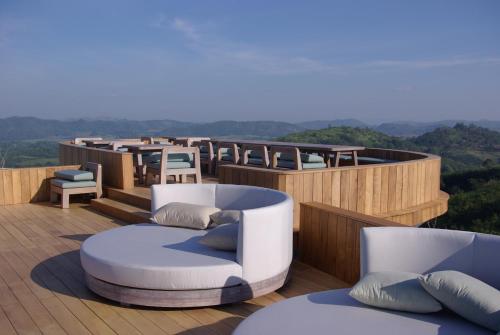 a deck with two couches and a table and chairs at Sala Khaoyai in Wangkata