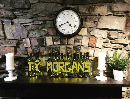 a clock on a stone wall with bottles and candles at Ty Morgan's in Rhayader