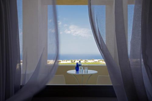 a window with a table with a bottle on it at The Majestic Hotel in Fira