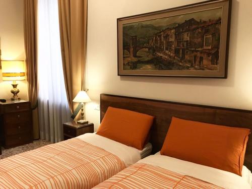 ローマにあるNori Guest Houseのベッドルーム1室(ベッド2台付)が備わります。壁には絵画が飾られています。