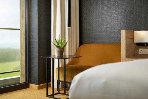 a bedroom with a table and a chair and a bed at Van Der Valk Luxembourg Arlon in Arlon