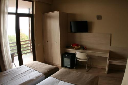 a bedroom with a bed and a desk with a television at Savaneti Eco Hotel in Tʼelavi