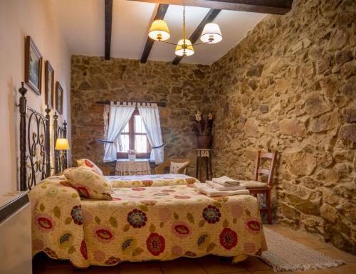 a bedroom with a bed and a stone wall at El Cerrillo in Navaconcejo