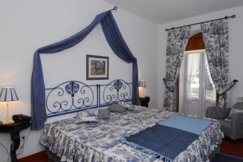 a bedroom with a blue and white bed and a chair at Quinta de Coalhos TH in Abrantes