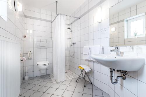 a white bathroom with a sink and a toilet at Hotel am Rokokogarten in Veitshöchheim