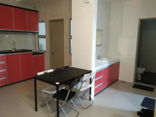 a kitchen with red cabinets and a black table and chairs at NAUFAL MUSLIM'S HOMESTAY in Cameron Highlands