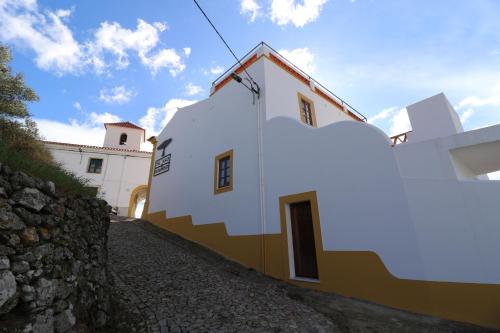 a white and yellow building with a stone wall at The Place at Evoramonte in Évora Monte