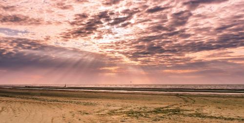 a beach with a cloudy sky and the ocean at Hotel Prado in Ostend