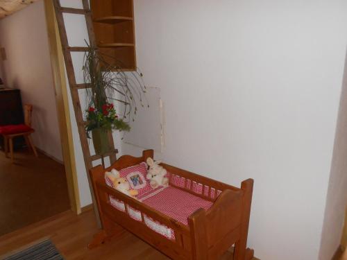 a stuffed animal sitting on a bench next to a ladder at La vecchia Mesnerhaus in Pusterwald