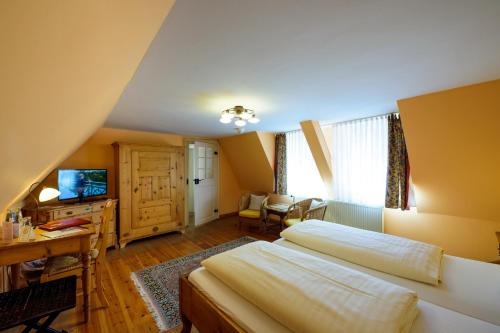 a bedroom with two beds and a desk and a television at Hotel Theophano in Quedlinburg