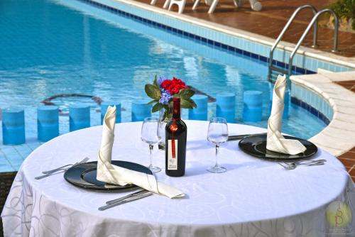 a table with a bottle of wine and glasses next to a pool at Hotel L'Ulivo in Girasole