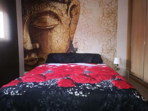 Schlafzimmer mit einem Bett mit einer roten und blauen Decke in der Unterkunft La casona de flores in Fuensalida