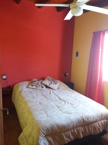 ein Schlafzimmer mit einem Bett mit einer roten Wand in der Unterkunft Casas del Mar in San Bernardo