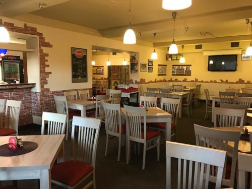 a restaurant with tables and white chairs and a unintention at Hotel Zimní stadion Náchod in Náchod