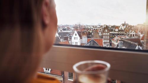 a person looking out of a window at a city at WestCord City Centre Hotel in Amsterdam