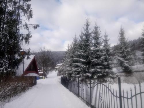 a fence covered in snow next to a house at Dom "Honorat", Kamianna 70, 33-336 in Kamianna