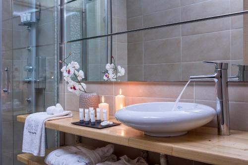 a bathroom with a sink and a shower with candles at Callia Retreat Suites - Adults Only in Fira