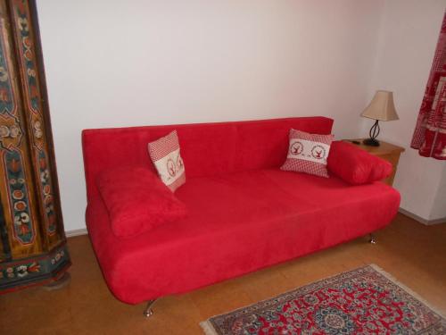 a red couch with two pillows on it in a living room at La vecchia Mesnerhaus in Pusterwald