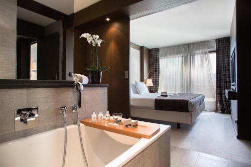 a bathroom with a bath tub and a bedroom at Crans Ambassador in Crans-Montana