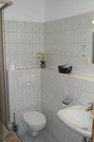 a white bathroom with a toilet and a sink at Hotel-Stadt-Aschersleben in Aschersleben