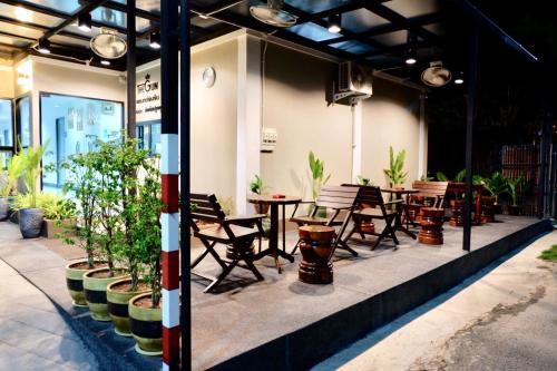 a patio with tables and chairs and potted plants at The Gun Hotel in Surin