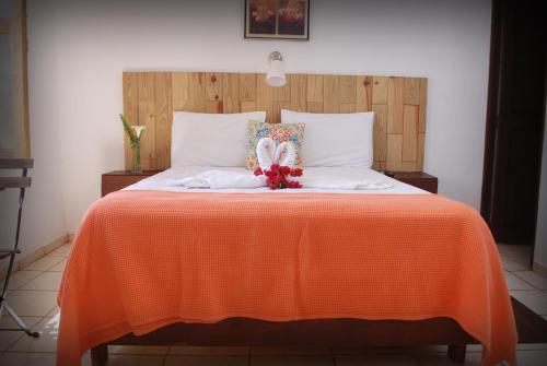 a bed with an orange blanket and a stuffed bunny on it at Hotel Rancho Constanza & Cabañas de la Montaña in Constanza
