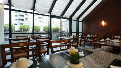 a dining room with tables and chairs and windows at Bristol Metropolitan Curitiba Centro in Curitiba