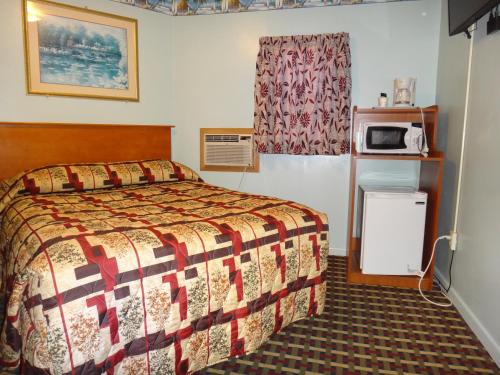 a hotel room with a bed and a microwave at Pine Ridge Motel in Dodgeville