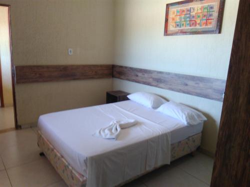 1 dormitorio con cama blanca y cabecero de madera en Hotel Imperial, en Palmeira dos Índios