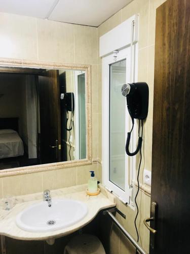 a bathroom with a sink and a phone on the wall at Hotel Cervantes in Zafra