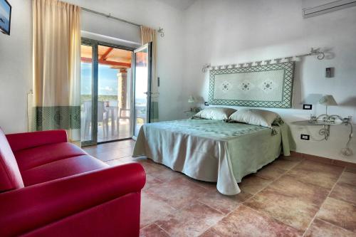a bedroom with a bed and a red couch at Country House Vignola Mare in Aglientu