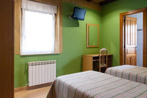 a green bedroom with two beds and a window at Pensión la Campanilla in La Penilla