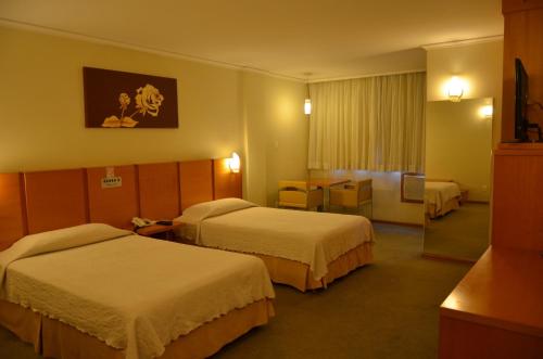 a hotel room with two beds and a table at Barbur Plaza Hotel in Ponta Grossa
