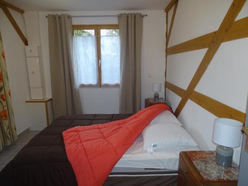a bedroom with a bed with a red blanket on it at Gite de l'étang in Belval-en-Argonne