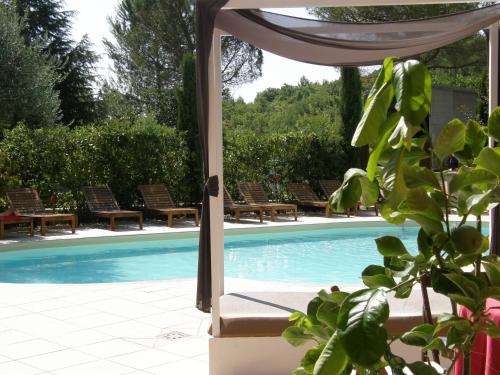 a swimming pool with chairs and a table and a plant at El Patio Hotel in Corciano