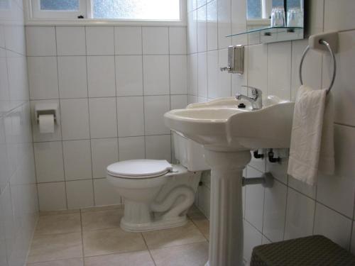 a white bathroom with a toilet and a sink at Portal Austral in Puerto Montt