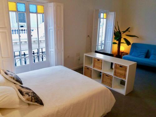 um quarto com uma cama branca e um sofá azul em Apartamento Foro Romano em Cartagena