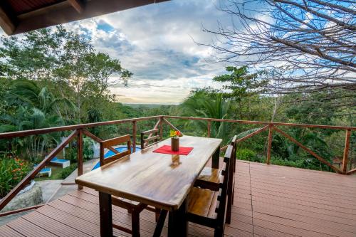 a wooden deck with a table and chairs on it at Hotel Cerro Lodge in Tarcoles